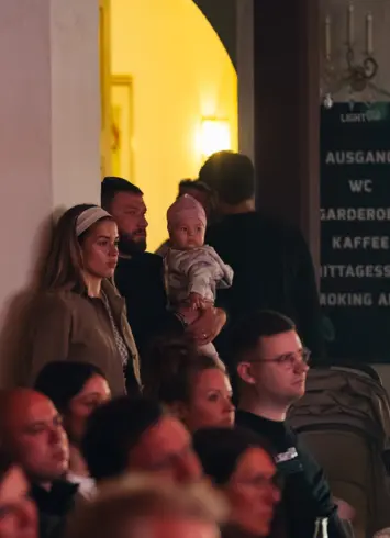 Ein Pärchen das mit einem Baby an einer Säule steht