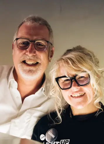 Ein Mann und eine Frau, die in die Kamera lächeln