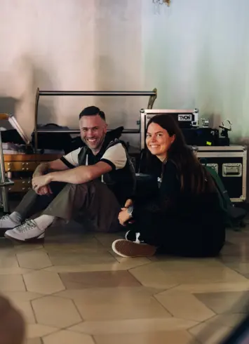 Ein Mann und eine Frau, die auf dem Boden sitzen und zur Kamera lächeln
