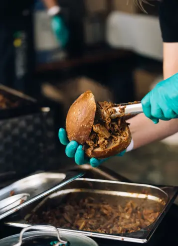 Ein Pulled Pork Burger, der gerade gefüllt wird